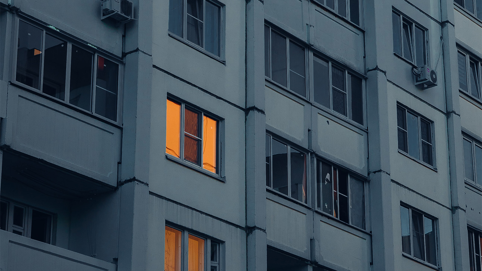 A window lit up in an apartment building at dusk.
