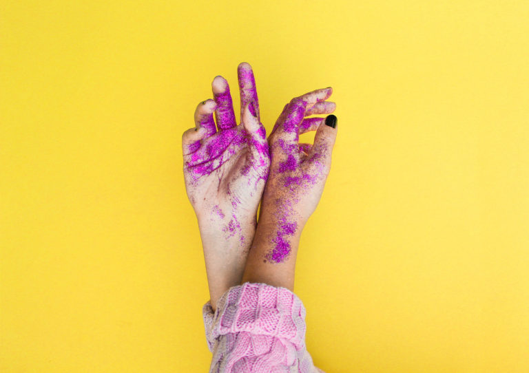 A pair of hands covered in purple glitter.